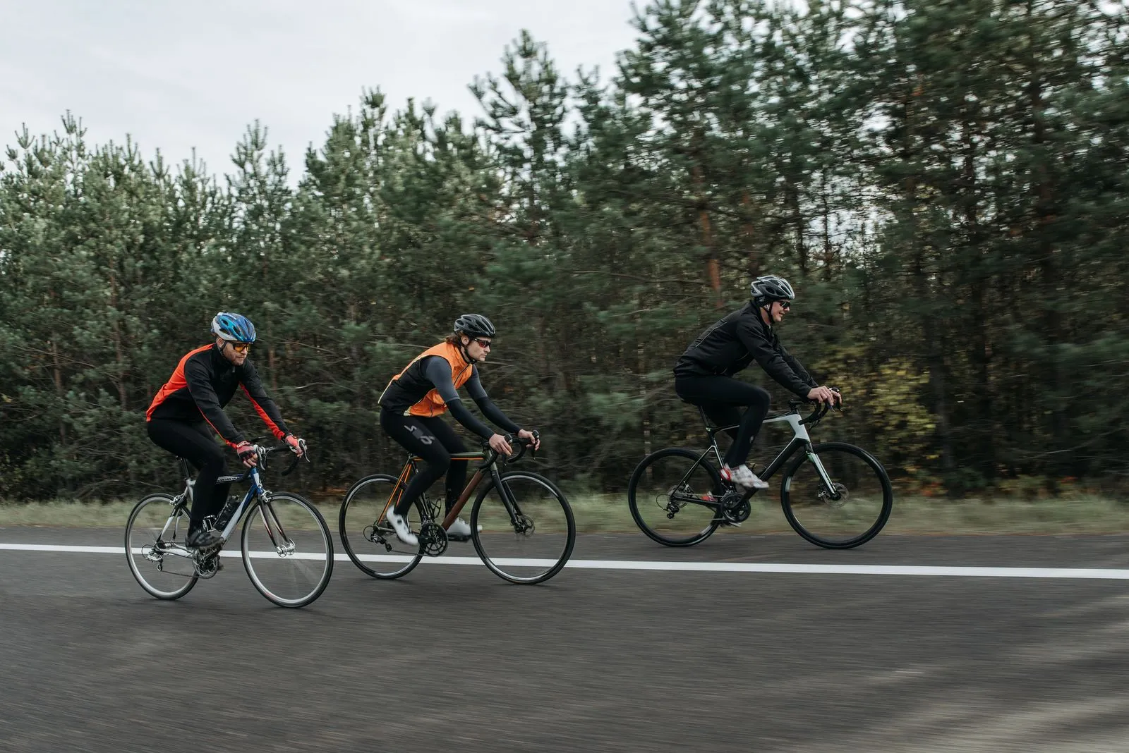 Group of cyclists riding bikes outdoors through a scenic forest area.